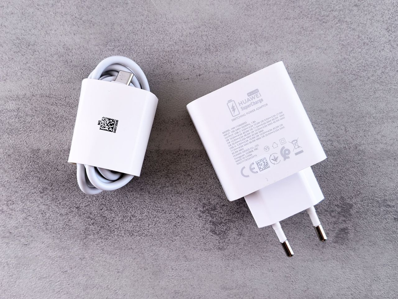 White charger and USB cable displayed on a grey textured surface, showcasing sleek design.