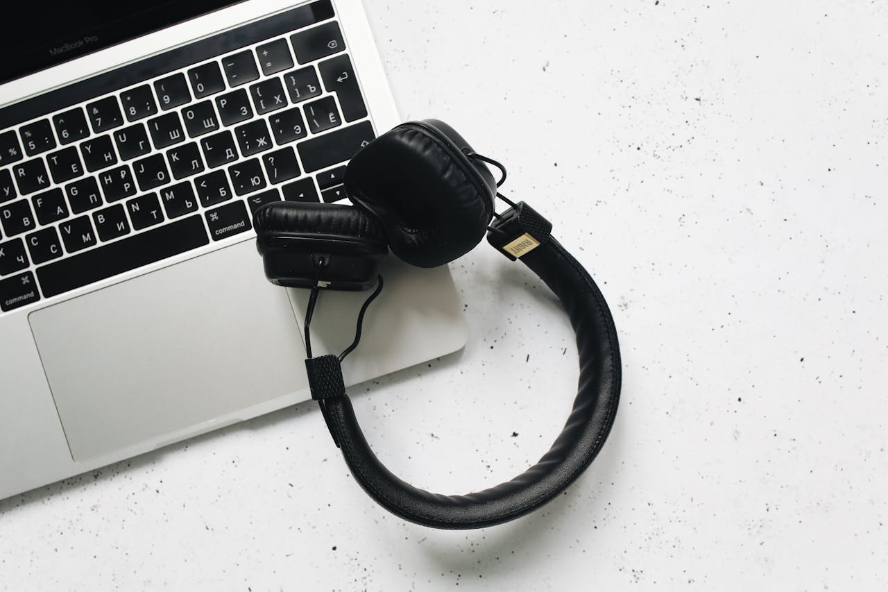 Overhead view of a laptop and headphones on a stylish marble background.