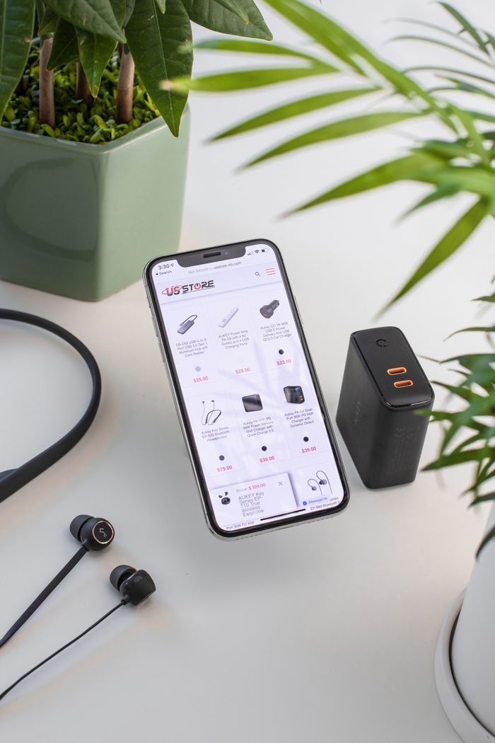 From above composition of modern mobile phone placed on working desk near uninterruptible power supply and wired earphones